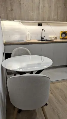a white table and chairs in a kitchen with a sink at Cozy apartment in Podgorica in Podgorica