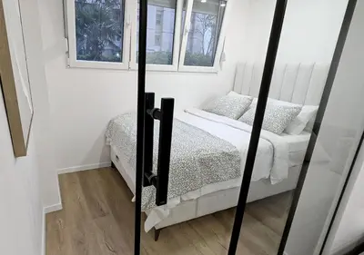a small bedroom with a bed and two windows at Cozy apartment in Podgorica in Podgorica