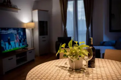 a table with a bottle of wine and a vase with a plant at Gorica Apartment in Podgorica