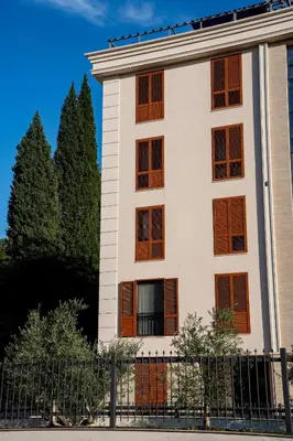 a white building with brown windows and a fence at Gorica Apartment in Podgorica