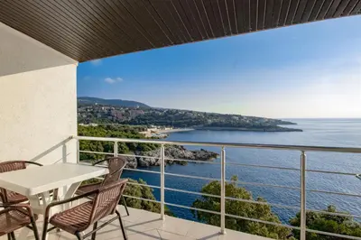 a balcony with a table and chairs and the ocean at Aleksandra Apartments Utjeha in Utjeha