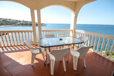 a table and chairs on a balcony with the ocean at Aleksandra Apartments Utjeha in Utjeha