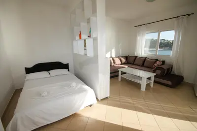 a white bedroom with a bed and a couch at Aleksandra Apartments Utjeha in Utjeha