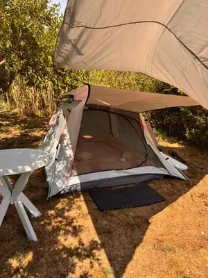 a tent sitting on the ground next to a chair at Greenfield campsite in Donji Štoj