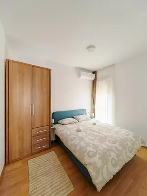 a bedroom with a large bed and a wooden cabinet at Modern City Apartment Budva-Central Location,5 min to Beach in Budva