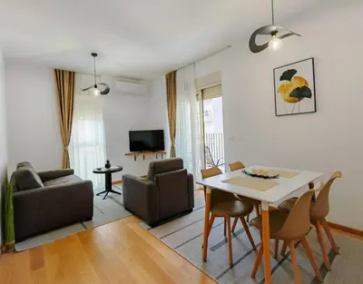 a living room with a table and chairs and a dining room at Modern City Apartment Budva-Central Location,5 min to Beach in Budva