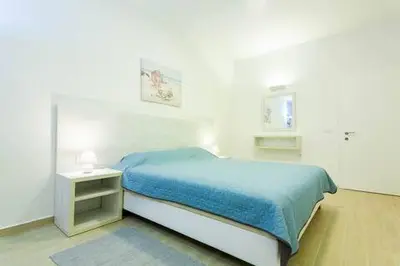 a white bedroom with a blue bed and a night stand at LAReina- Best Buy in Ulcinj