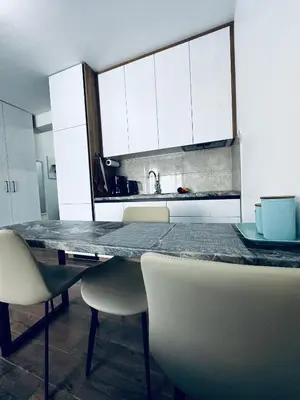 a kitchen with a table with chairs and white cabinets at Apartment Comfort A15 in Bar