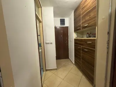 a small kitchen with wooden cabinets and a hallway at Modern Apartment Free Parking Near Center in Podgorica