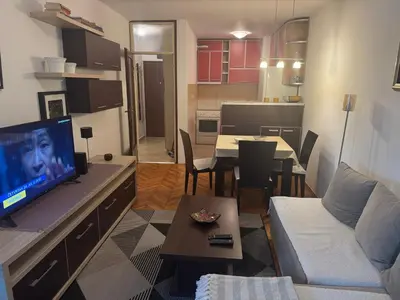 a living room with a couch and a tv and a kitchen at Modern Apartment Free Parking Near Center in Podgorica