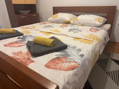a bed with a comforter with leaves on it at Modern Apartment Free Parking Near Center in Podgorica