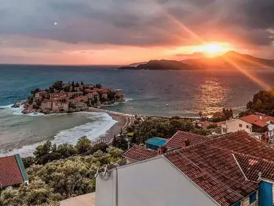 a sunset over a beach with houses and the ocean at Studio Maris in Budva