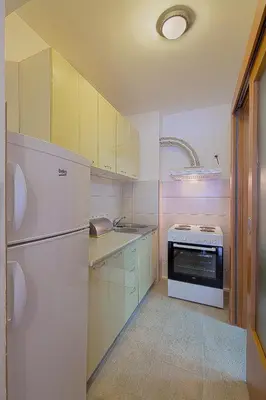 a kitchen with white cabinets and a sink and a stove at Studio Maris in Budva