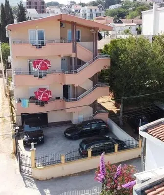 a building with cars parked in a parking lot at Ago Apartman in Dobra Voda