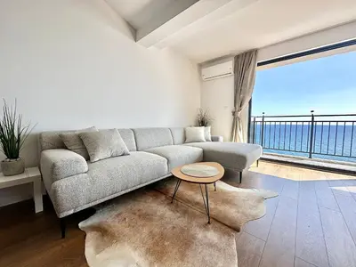 a living room with a couch and a large window at Seaview Retreat Reževići in Reževići