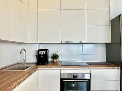 a kitchen with white cabinets and a sink at Seaview Retreat Reževići in Reževići