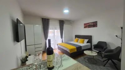a bedroom with a bed and a table with a bottle of wine at Premium City Kvart Apartment in Podgorica