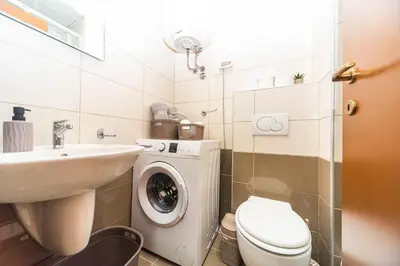 a bathroom with a toilet sink and a washing machine at Premium City Kvart Apartment in Podgorica