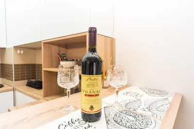 a bottle of wine sitting on a counter with two glasses at Premium City Kvart Apartment in Podgorica