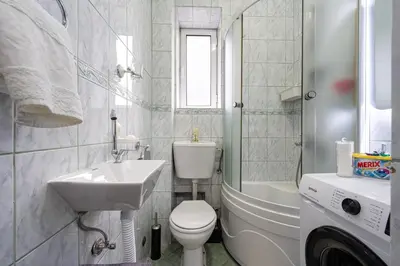 a white bathroom with a sink and a toilet at Downtown Apartment Freedom in Podgorica