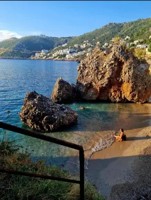 a person sitting in the water on a beach at HELEN LUX Apartments in Dobra Voda