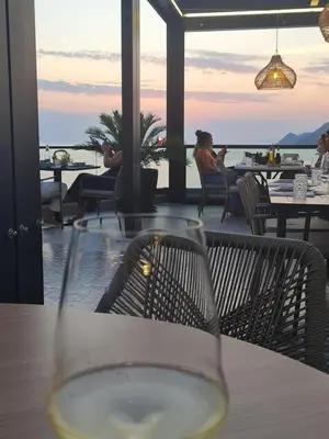 a glass of wine sitting on a table in a restaurant at HELEN LUX Apartments in Dobra Voda