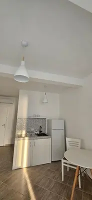 a white kitchen with a table and a white refrigerator at Hotel Kunjui in Utjeha