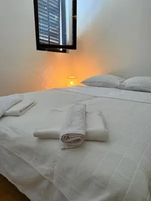 a white bed with two towels on top of it at Coral apartment in Budva