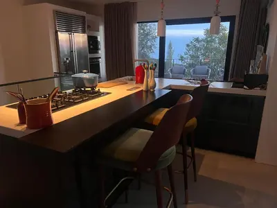a kitchen with a counter with a stove and chairs at Vila panorama in Budva