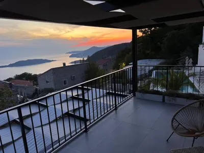a balcony with a view of a sunset on the water at Vila panorama in Budva