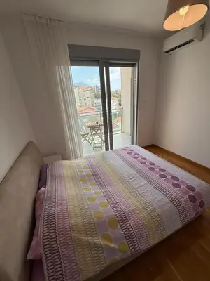 a bedroom with a bed and a balcony with a view at Mediterano apartment Becici in Budva
