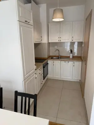 a kitchen with white cabinets and a sink and a table at Mediterano apartment Becici in Budva