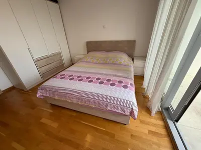 a small bed in a room with a wooden floor at Mediterano apartment Becici in Budva