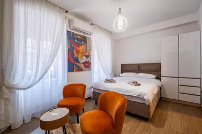 a bedroom with a bed and two chairs and a table at Apartman Ksenija in Cetinje