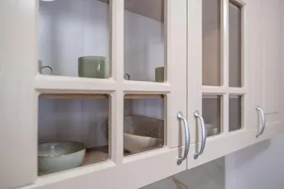a white cabinet with glass doors with a bowl at Apartman Ksenija in Cetinje