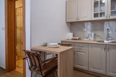 a kitchen with white cabinets and a wooden table at Apartman Ksenija in Cetinje