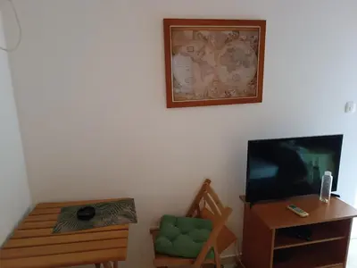 a living room with a tv and a chair and a table at Budva obala in Budva