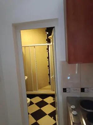 a bathroom with a glass door to a kitchen with a checkered floor at Budva obala in Budva