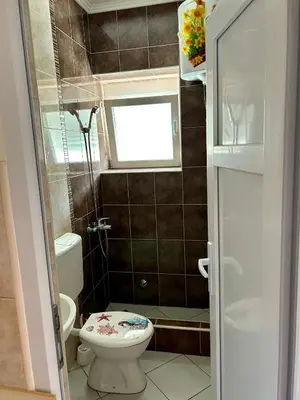 a small bathroom with a toilet and a window at Apartmani Vedrana Sutomore in Sutomore