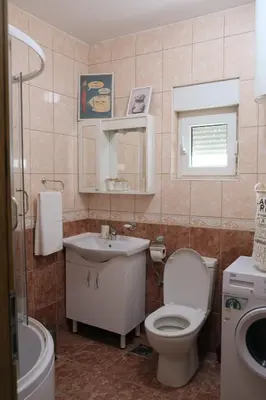 a bathroom with a toilet and a sink and a mirror at Olivers Cozy and Spacious Apt in Podgorica