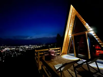 a house with a balcony with a table and chairs at night at Podgoricka Koliba