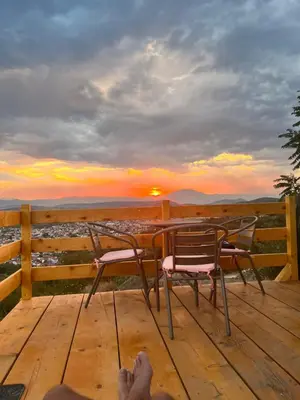 a person sitting on a deck watching the sunset at Podgoricka Koliba