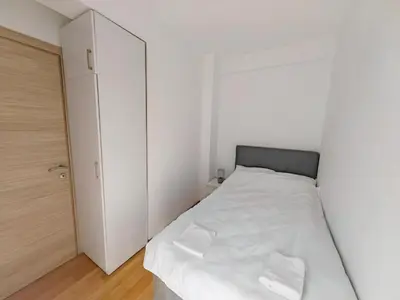a white bedroom with a bed and a closet at Modern City Apartment Budva 2-Central Location,5 min to Beach in Kravlja