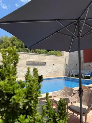 a black umbrella and chairs next to a swimming pool at Cozy Studio 11 Budvablue with Pool - Parking in Budva
