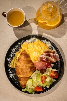 a black plate of breakfast food with eggs meat and salad at Skyline Sunset in Becici