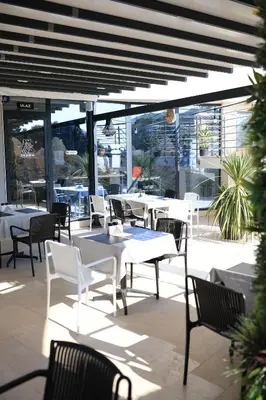 a patio with white tables and chairs and windows at Skyline Sunset in Becici