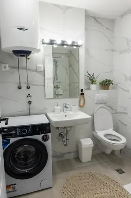 a bathroom with a washing machine and a sink at Floret Suite in Podgorica