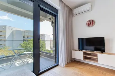 a living room with a tv and a sliding glass door at Aura Zafiro in Budva