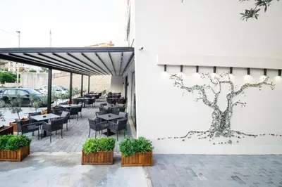 a patio with tables and chairs and a tree painted on the wall at Hedonist in Ulcinj