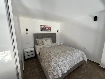 a small bedroom with a bed and a white wall at Hedonist in Ulcinj